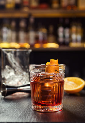 Glass of whiskey with lemon and ice cubes standing on the bar counter