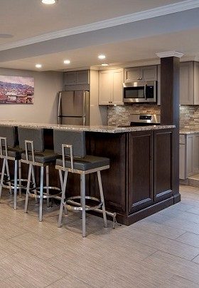 Kitchen with brown bar and three stools plus silver fridge, stove and microwave