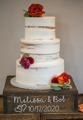 White 3 layer wedding cake with orange and burgundy flowers