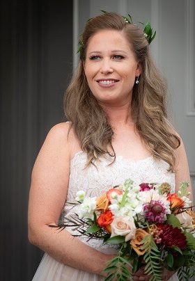 Bride holding floral arrangement with rust and burgundy flowers