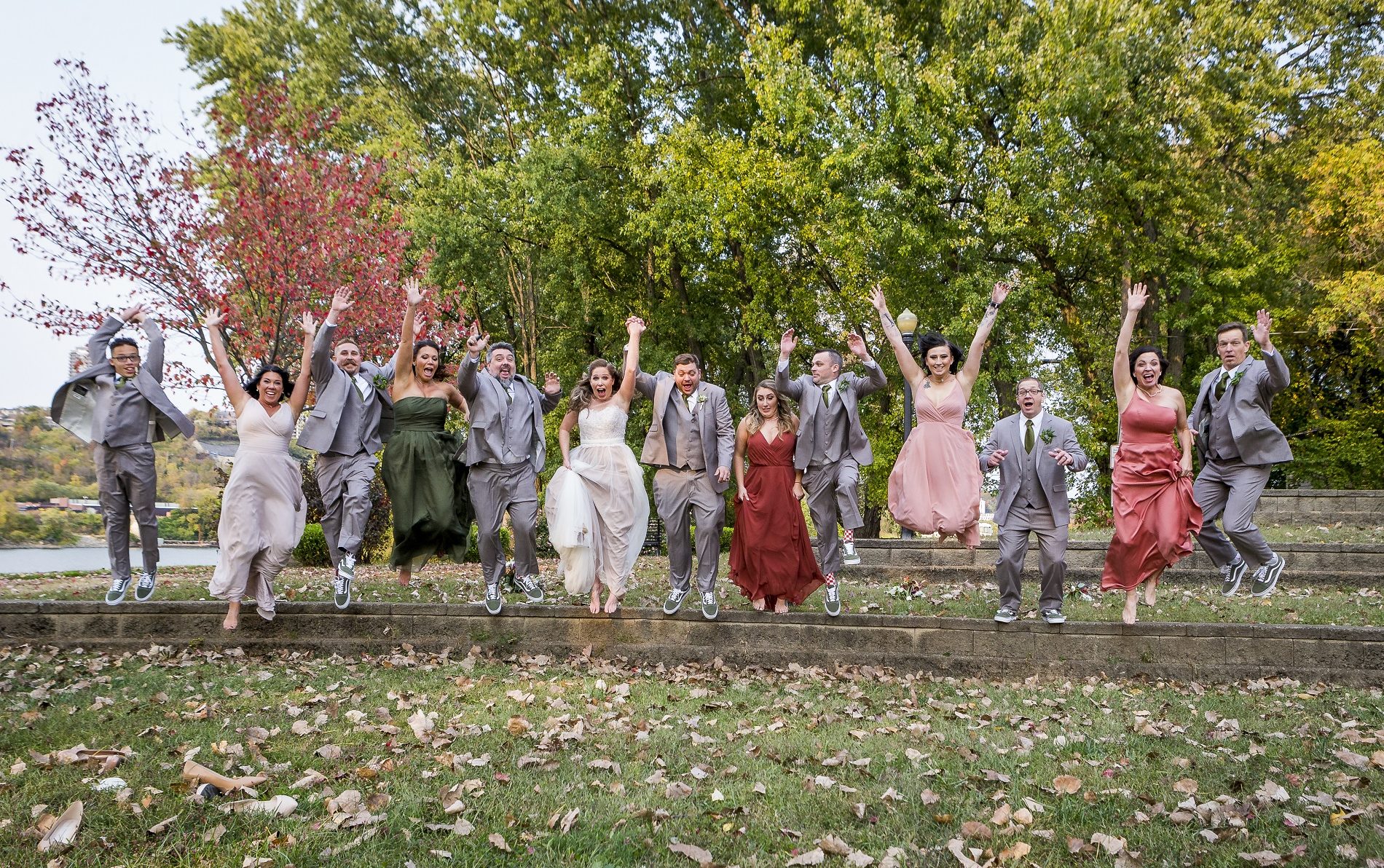 Group of ten men and women from a wedding jumping off a ledge