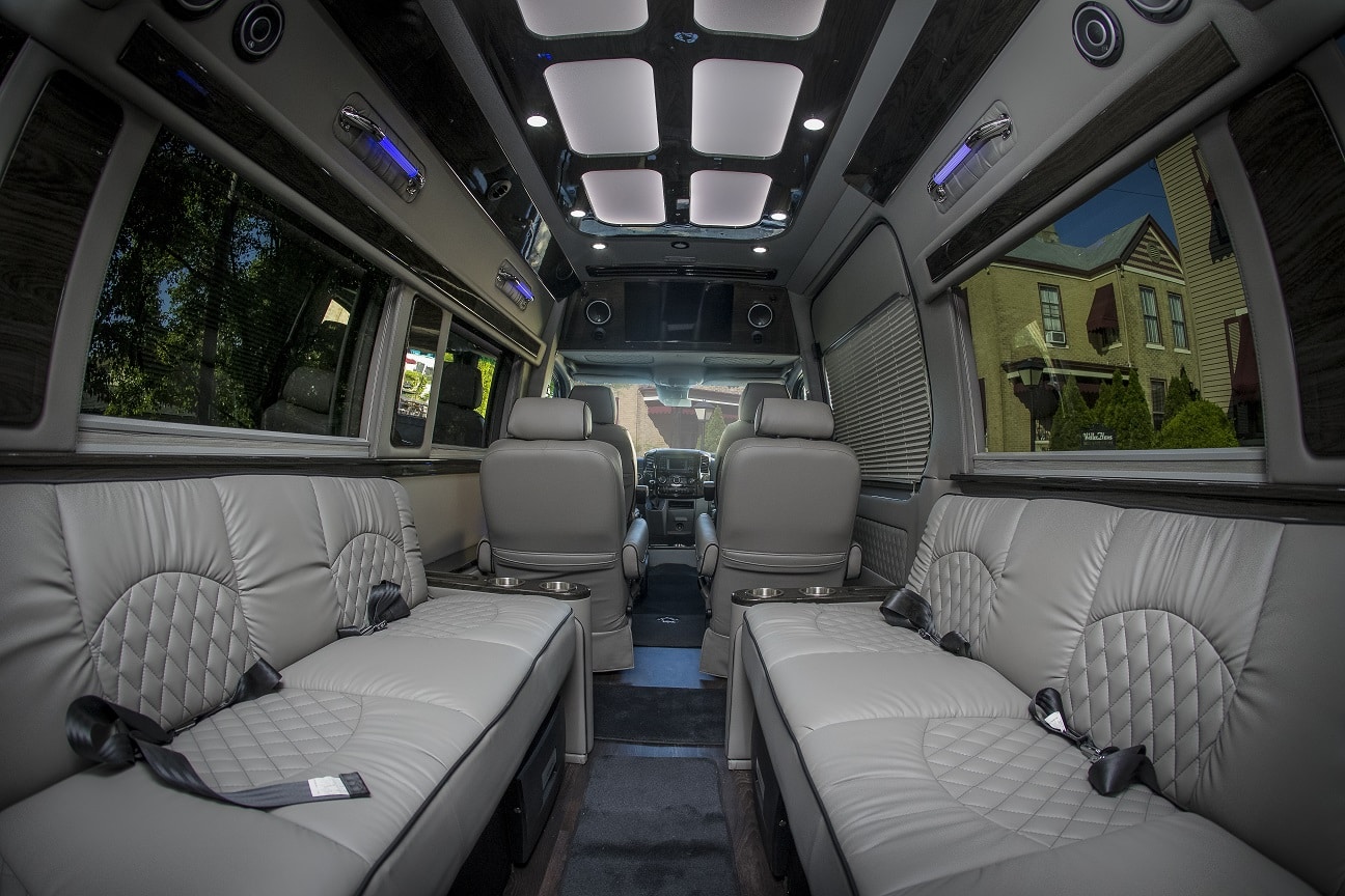 Inside of a luxury van with two gray bench seats and two captains chairs