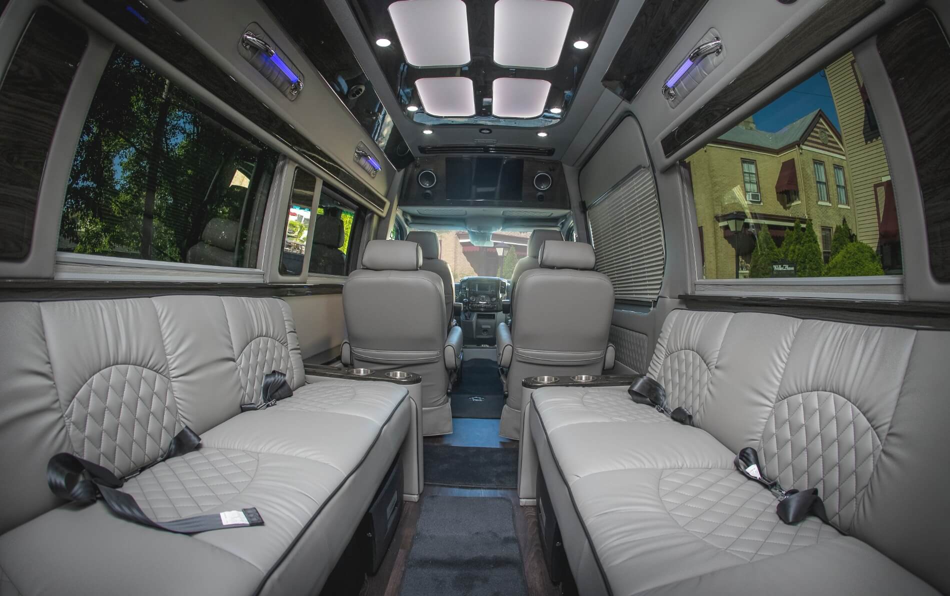 Inside of a luxury limousine with gray bench seats and two captains chair seats