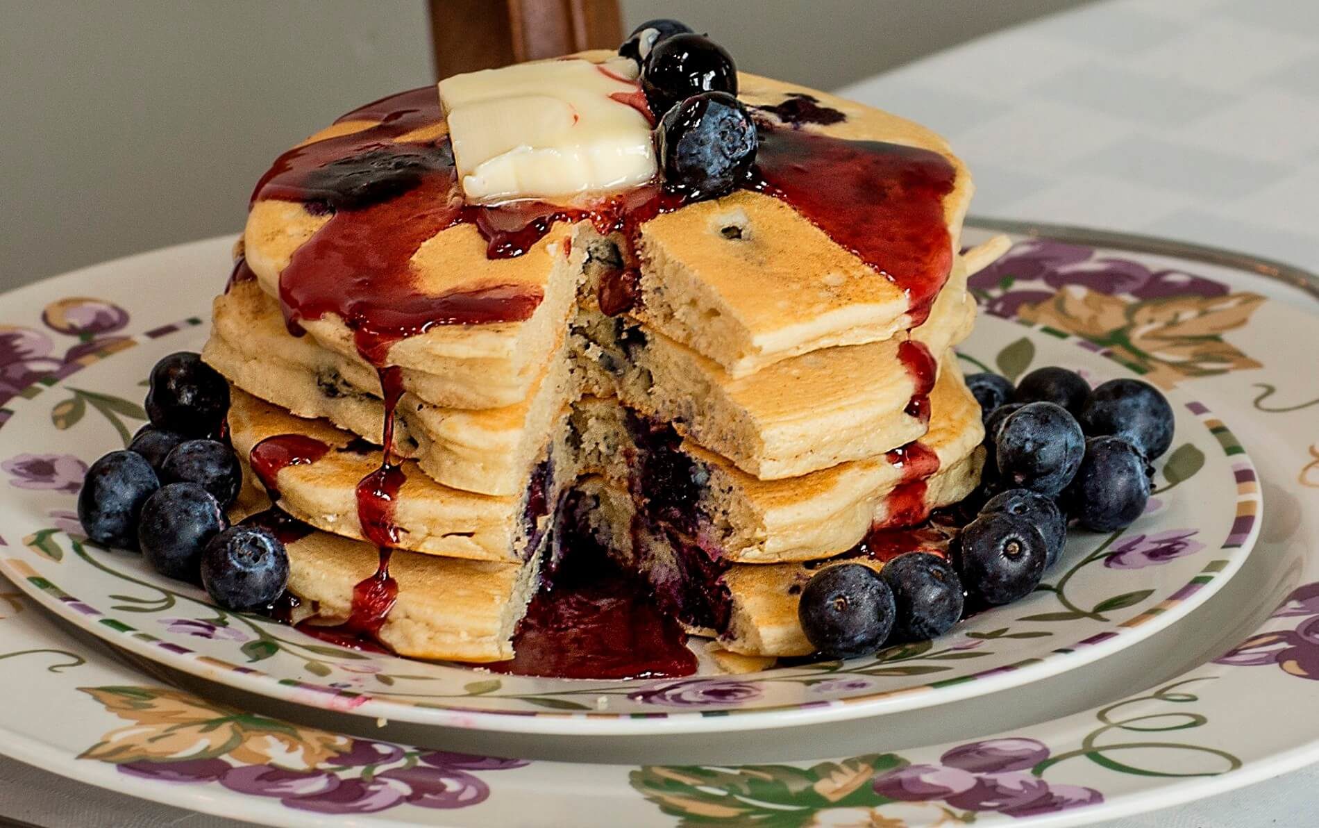 Purple flowered plates with stack of blueberry pancakes