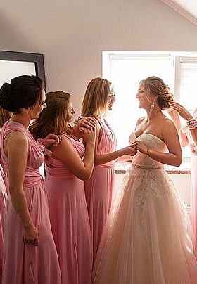 Bride in white dress surrounded by three bridesmaids in pink dresses