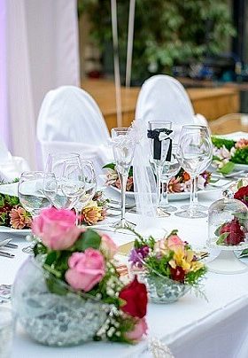 Table with white table cloths and red and pink flowers