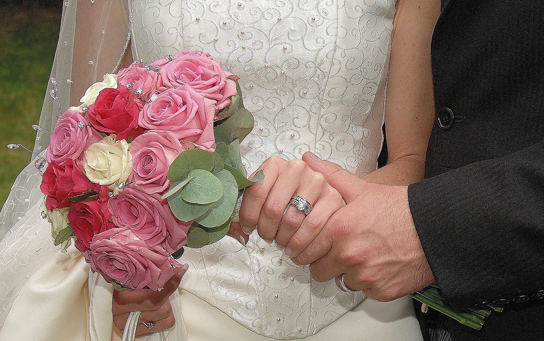 Bride in white dress with groom in black suite holding pink rose bouquet