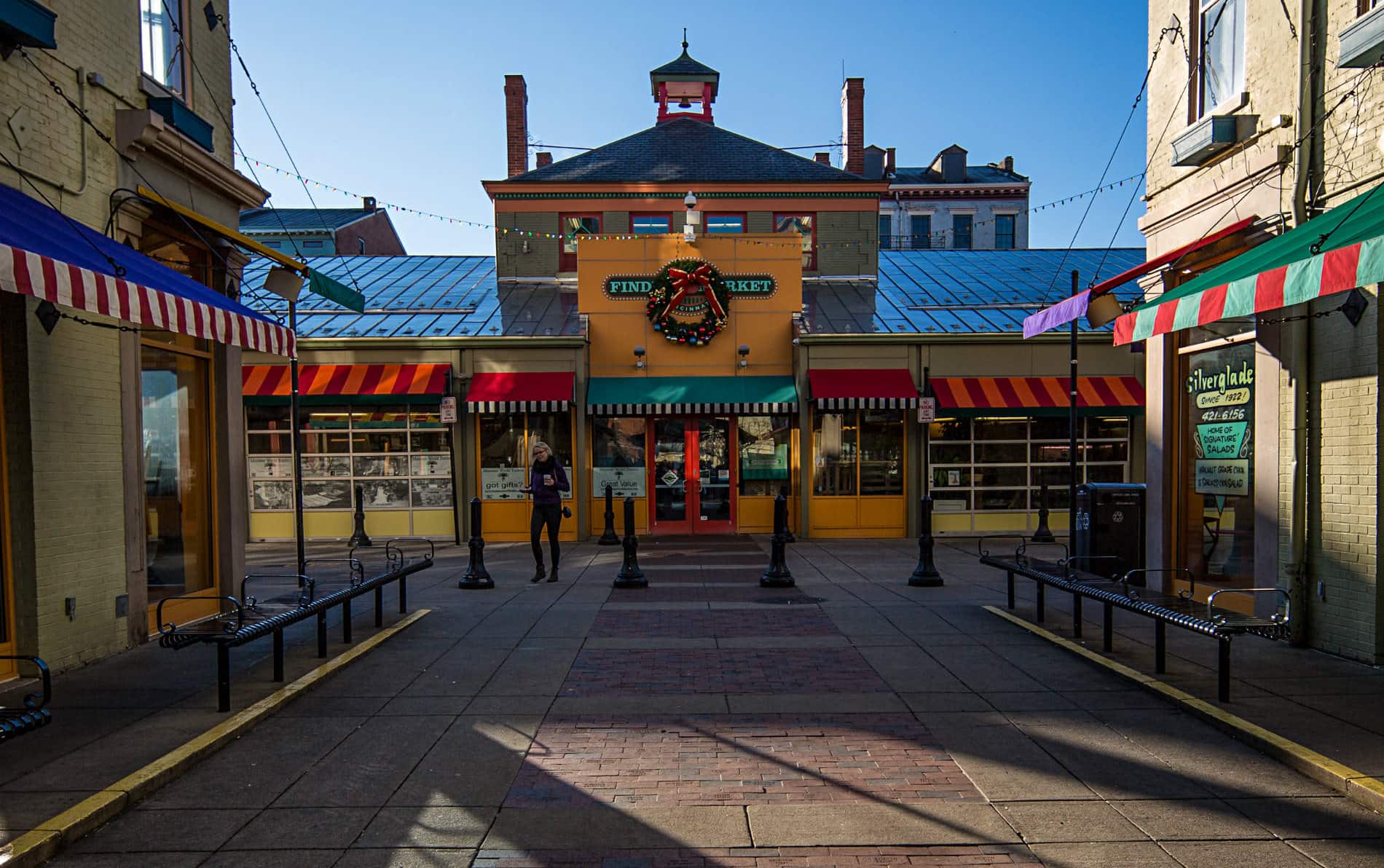 Orange two story building with blue metal roof and red and aqua canvas awnings with christmas wreath on front