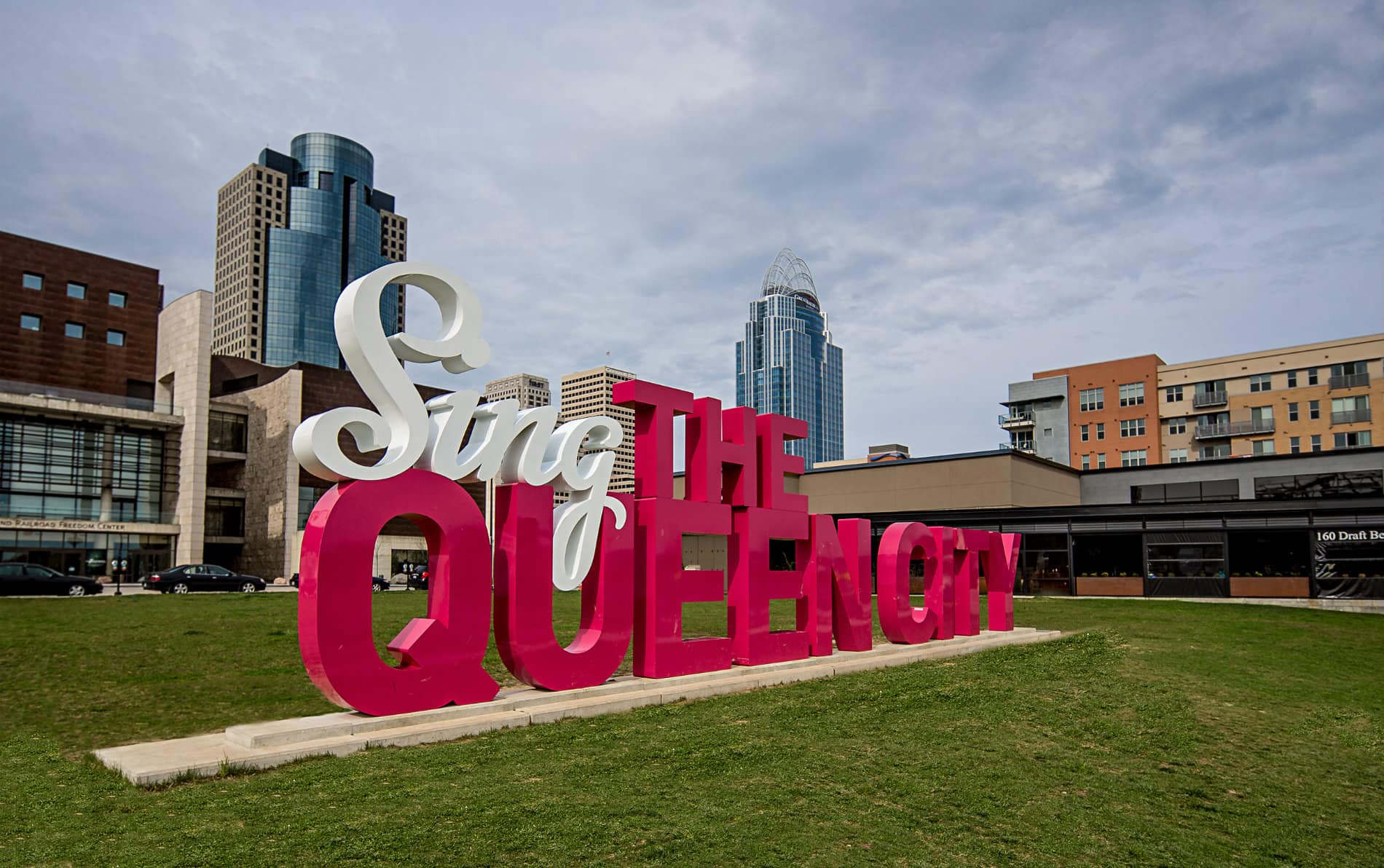 Large display sign in red and white letters spelling Sing the Queen City