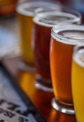 Closeup of craft beer samples on wood paddle outside at microbrewery