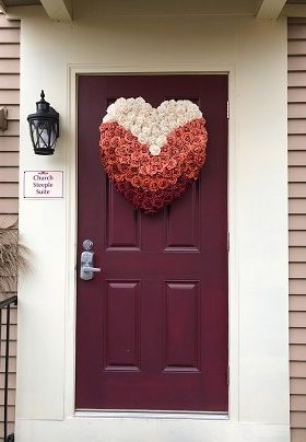 Red door with heart shaped floral of coral, rust and burgundy roses