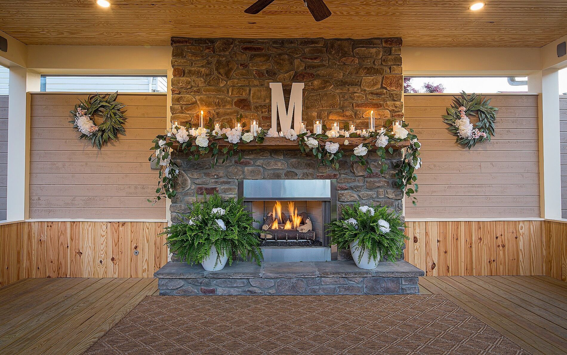 Lit brick fireplace with white flowers and burning candles on wooden mantle