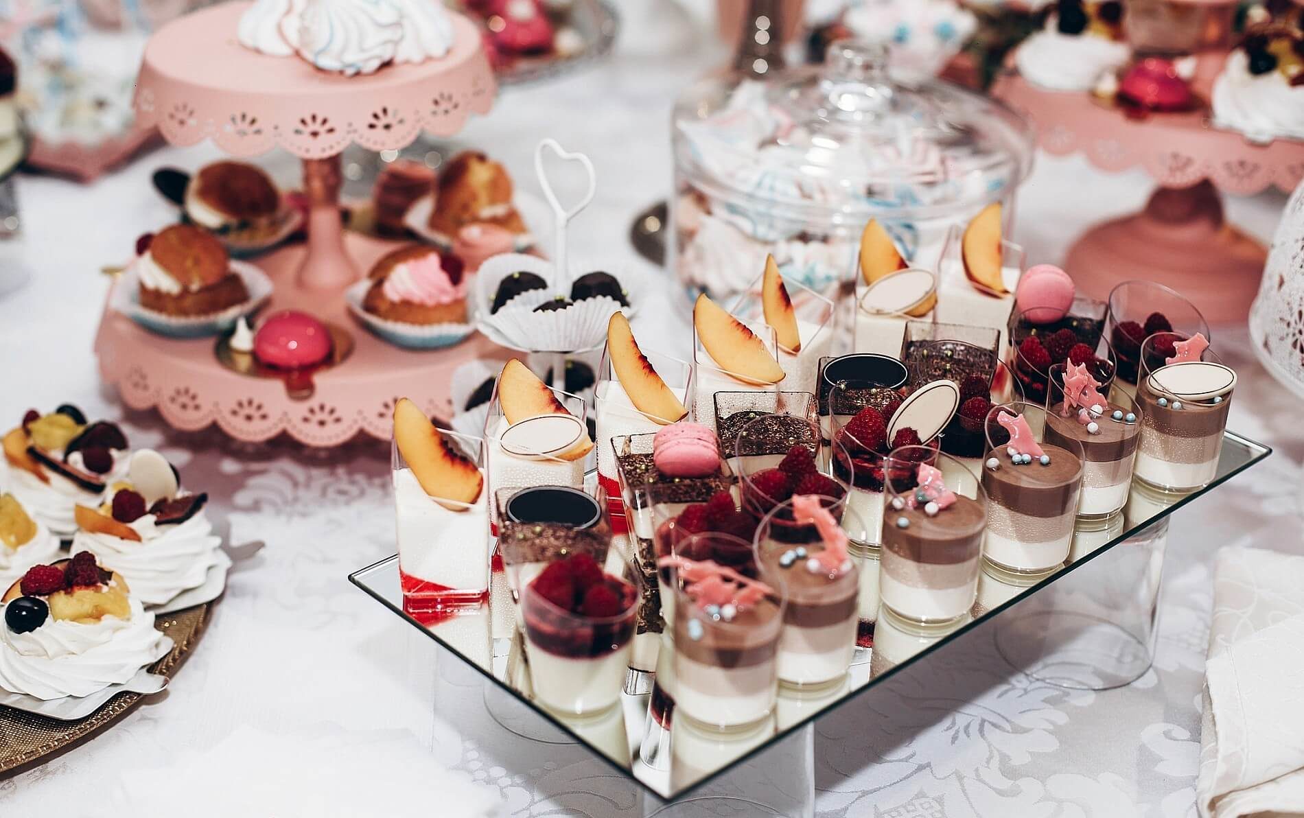 Table with dessert plates of chocolate pudding, fresh peaches, pink cookies