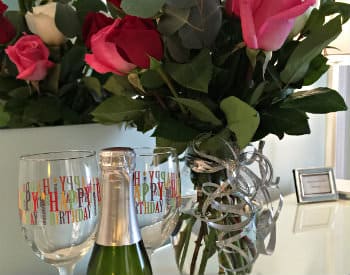 Large bouquet of pink, red and white roses, a small bottle of champange and two glasses imprinted with 'happy birthday'