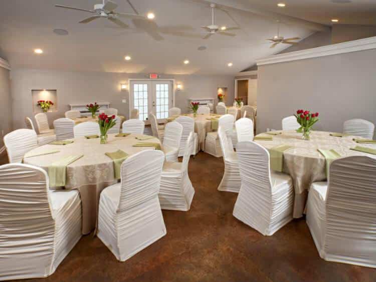 Large room with five lace covered tables, pale green napkins and red tulip centerpieces