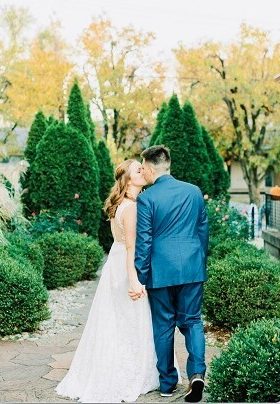 Bride and Groom kissing and holding hands in a garden