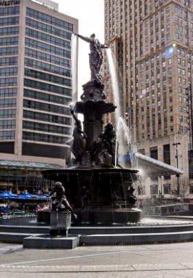 Two high rise buildings surrounding a multi-story black water fountain