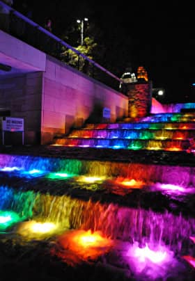 Nine stairs with purple, blue, green, yellow and red lights lighting up the water flowing down the stairs