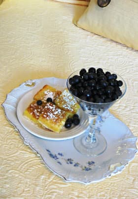 White rectangular china plate with blue flowers, a plate of lemon bars and dish of blueberries