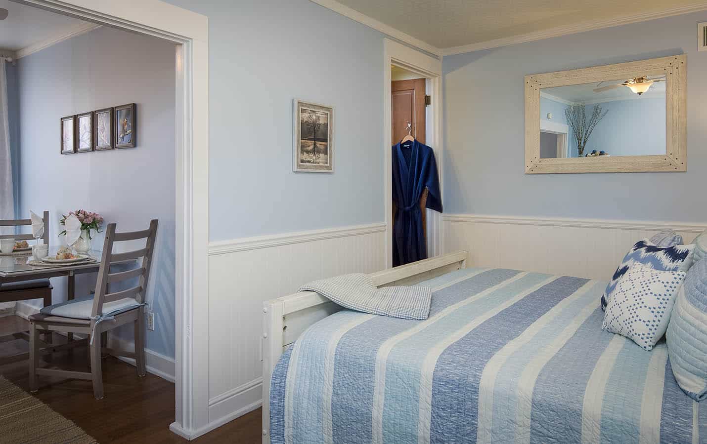 Footer of the bed and view of the bathroom entry.  Dark blue robe hanging in the bathroom