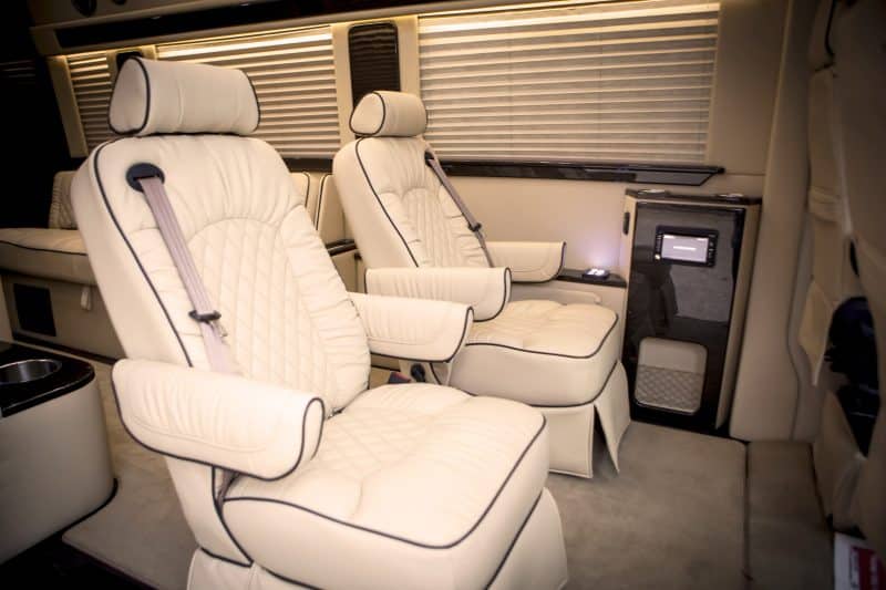 Two white armchair seats with black trim inside of Limousine